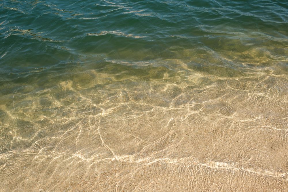 Clear sea water washing sandy shore