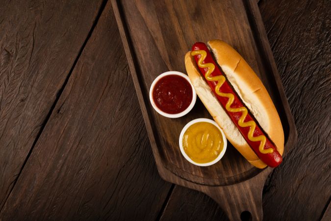 Top view of hot dog with mustard on wooden board with copy space