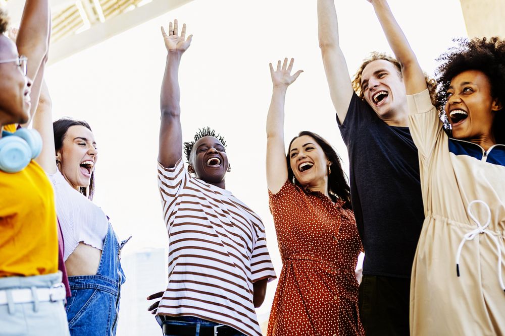 Group of young adults raising their hands in unity