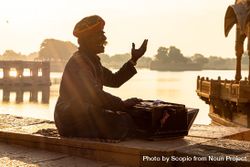 Sikh man sitting by the river at sunset 0gMg84