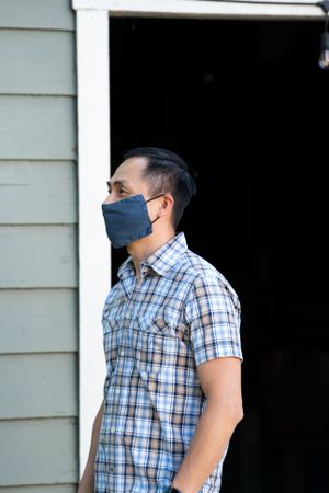 Portrait of man standing outside wearing COVID mask smiling and looking away