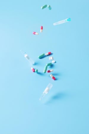 Variety of pills and pharmaceutical items falling on blue backdrop