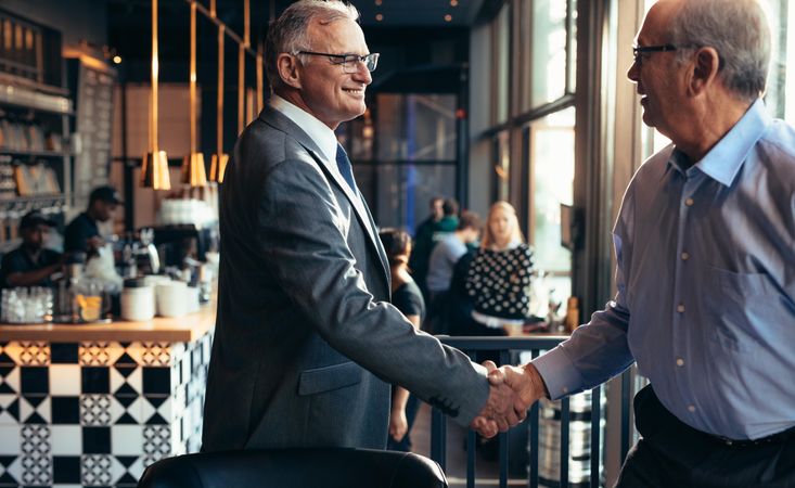 Mature businessman shaking hands with a man in restaurant