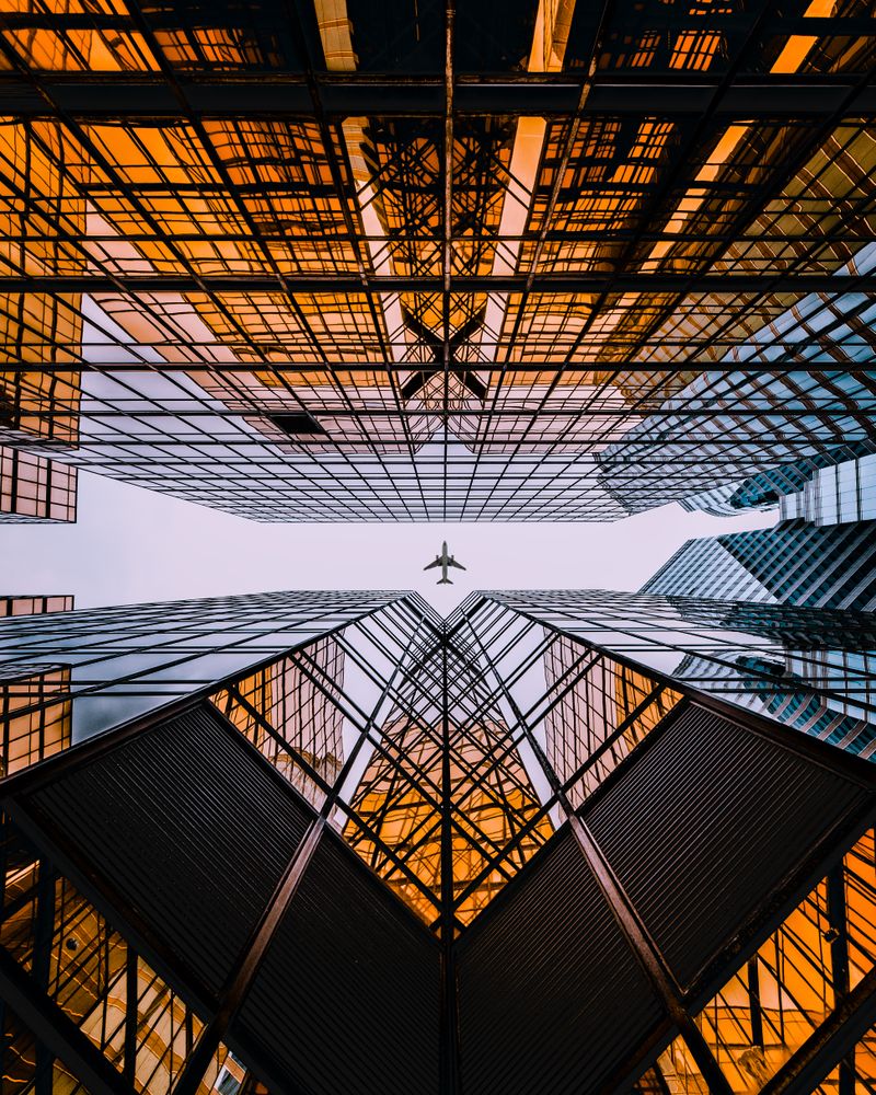 Low angle view of plane above city buildings