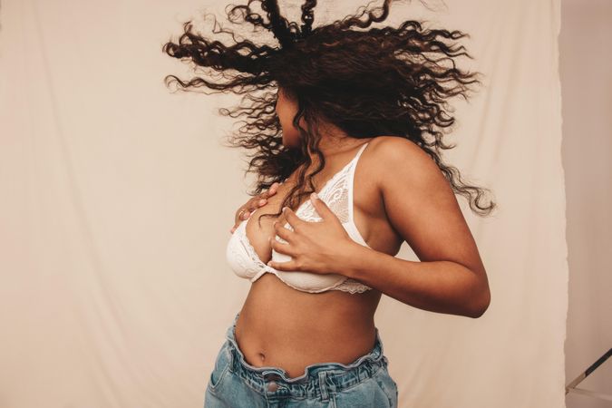 Young woman whipping her hair and embracing her body in a studio