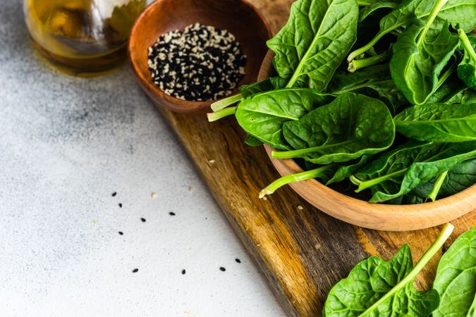 Wooden bowl of fresh spinach leaves on kitchen counter with space for text