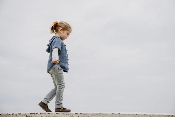 Girl balancing on border near sea