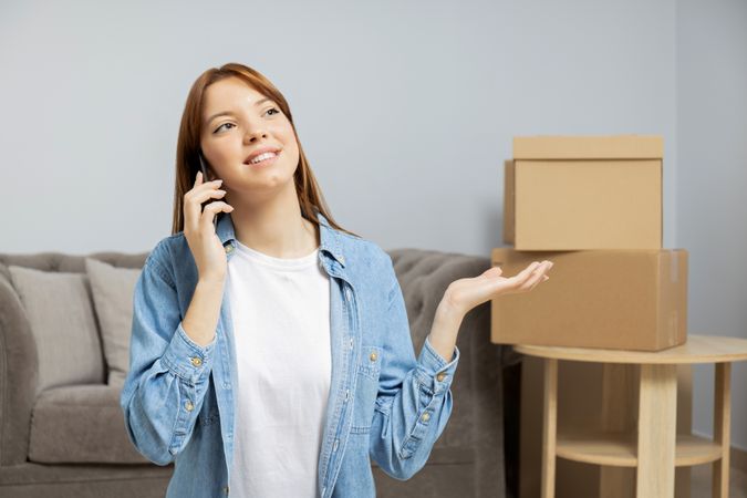 Moving concept, woman talking on the phone with boxes in the background.