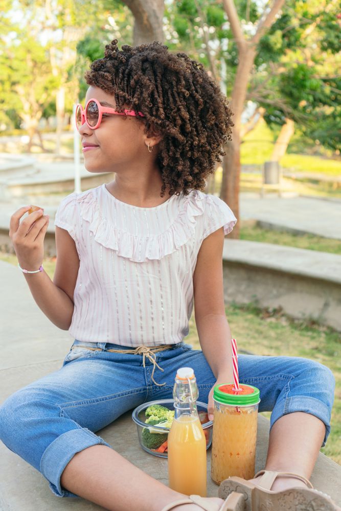 Girl eating vegetables during the day.