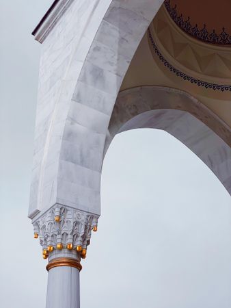 Gold on a light marble pillar in mosque with sky