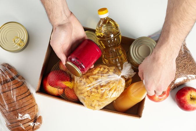 Young man puts groceries in donation box. Volunteer