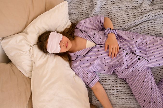 Teenage girl sleeping with a sleep mask.