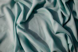 Nude green fabric wavy crumpled background texture with copy space.