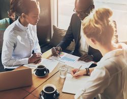 Three businesspeople focused on a chart at a cafe