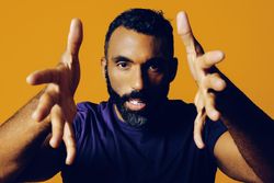 Serious Black man in yellow studio with hands surrounding the camera
