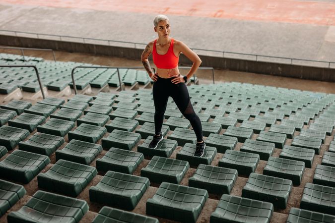 Fitness woman doing workout standing on the seats inside a stadium