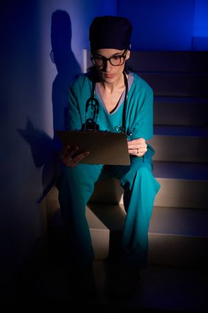 Female doctor sitting on stairs with clipboard