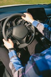 Young man holding steering wheel while driving the car