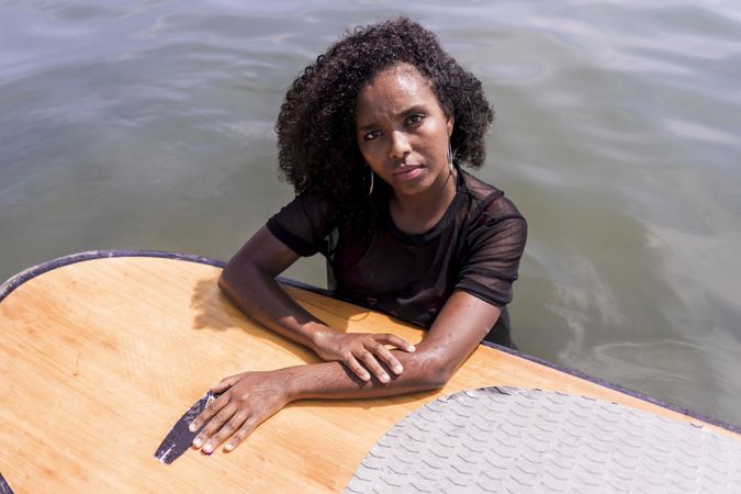 Young Black woman in the water next to paddle board