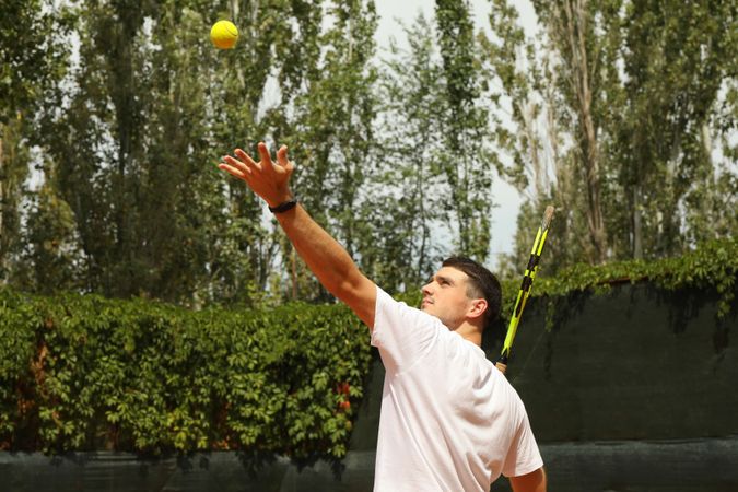 Young man in white t-shirt serve the tennis ball