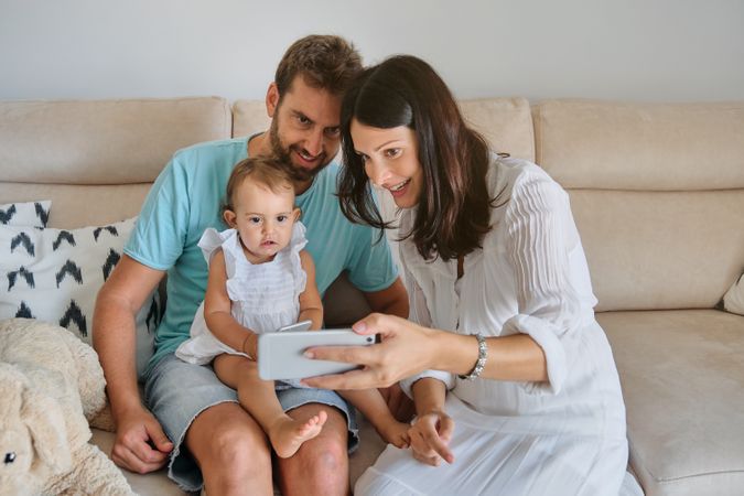 Parents with daughter watching smartphone at home