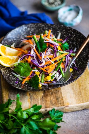 Fresh salad with finely chopped vegetables and lemon slices in bowl with copy space