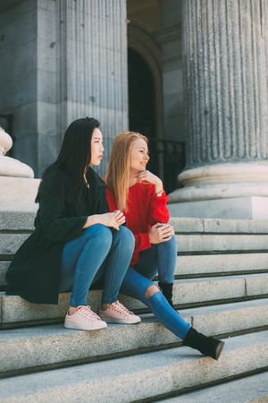 Female friends sitting on building steps