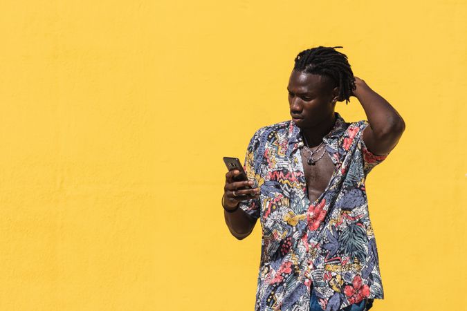 Stylish Black man in colorful shirt with smartphone