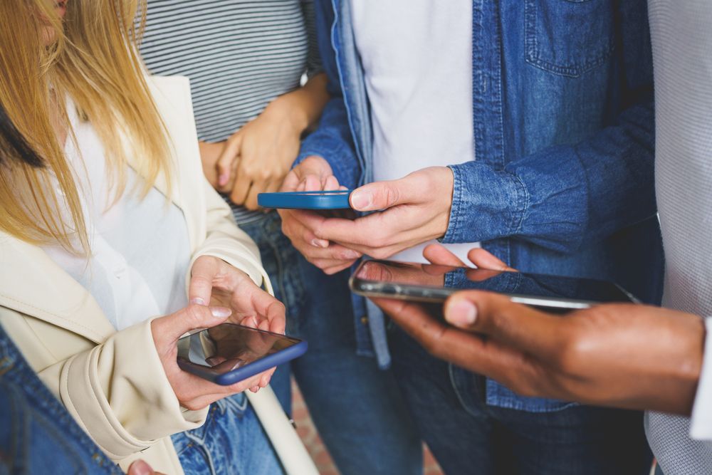 Group of people’s hands using their smart phones