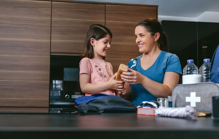 Mother preparing emergency backpack with her daughter