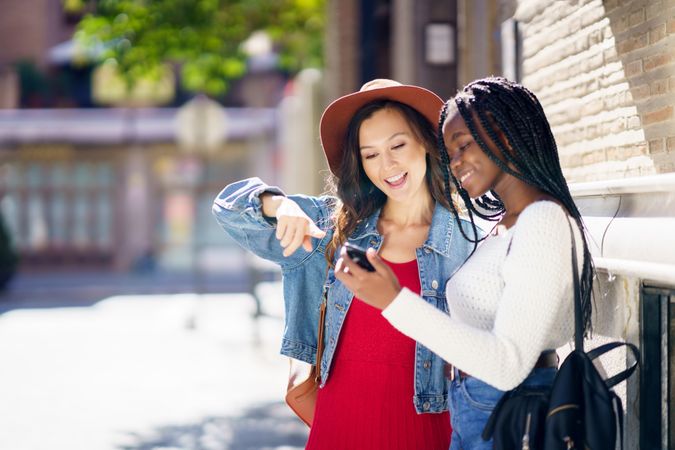 Female friends looking and pointing at a cell phone