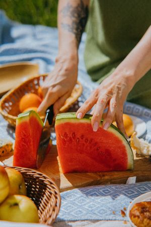 Cropped image of person cutting a watermelon in a picnic