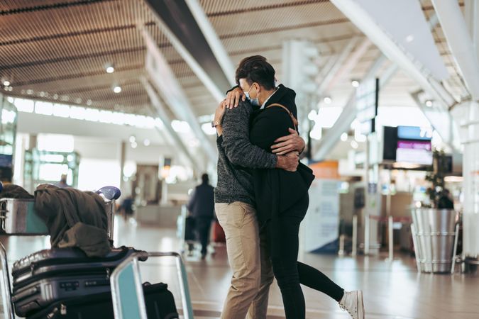 Woman hugging man after arrival from trip during pandemic