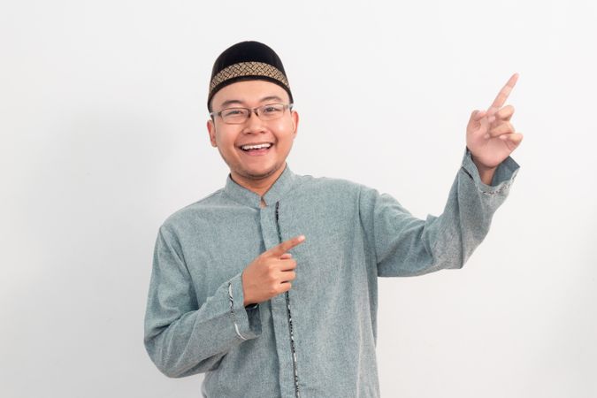 Asian Muslim man smiling doing pointing gesture in Ramadan