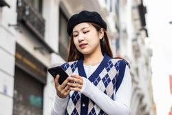 Young Asian Woman Walking and Using Smartphone in the City