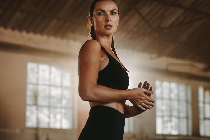 Fit woman standing inside abandoned warehouse after workout
