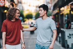 Cool multiracial male friends chatting while walking on street