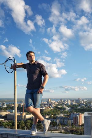 Man standing on roof holding onto pole