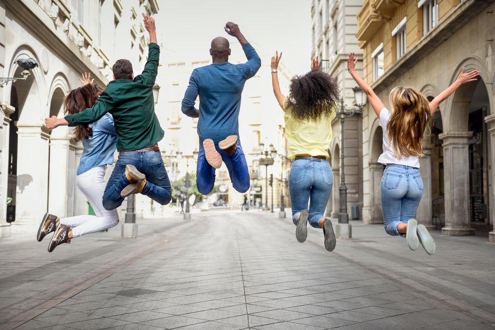 Back of group of people jumping in Spanish street