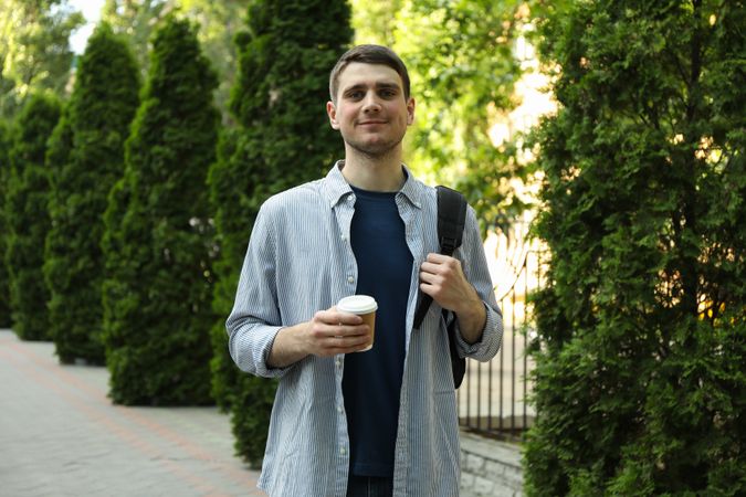 Young student hold backpack and cup of coffee. Study. University