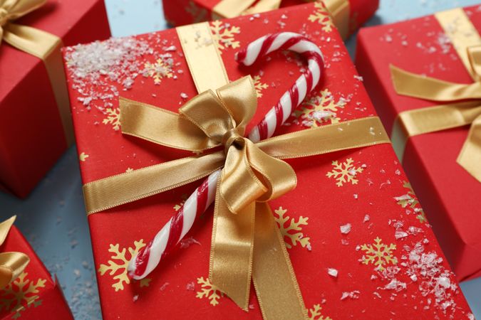 Gift box with candy cane on blue background, close up