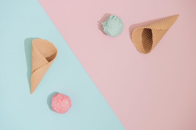 Ice cream cones with scoops of ice cream on pastel pink and blue background
