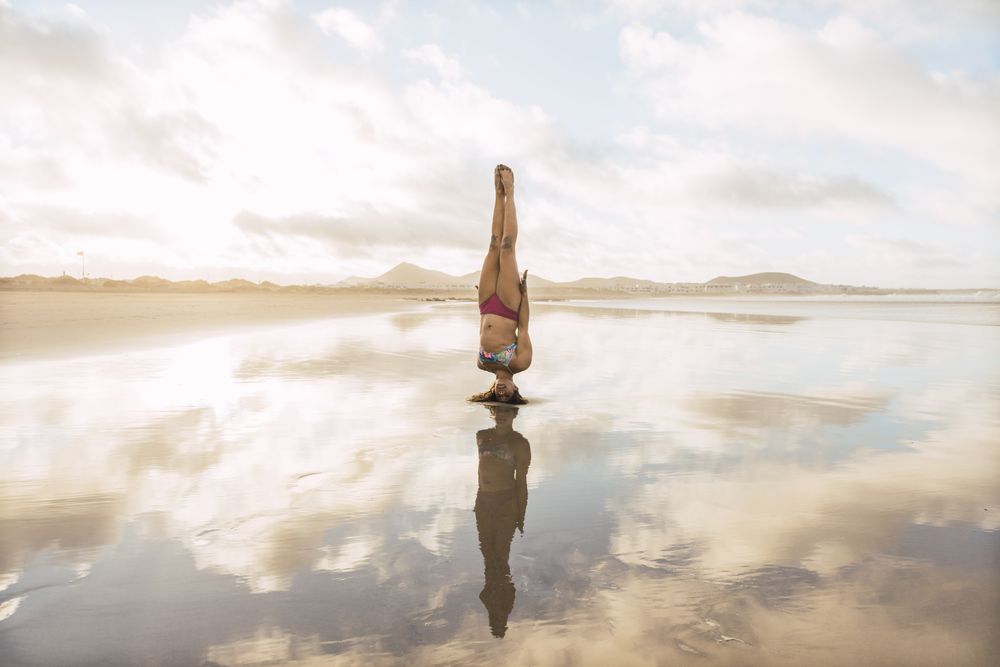 Woman doing handstand near sea