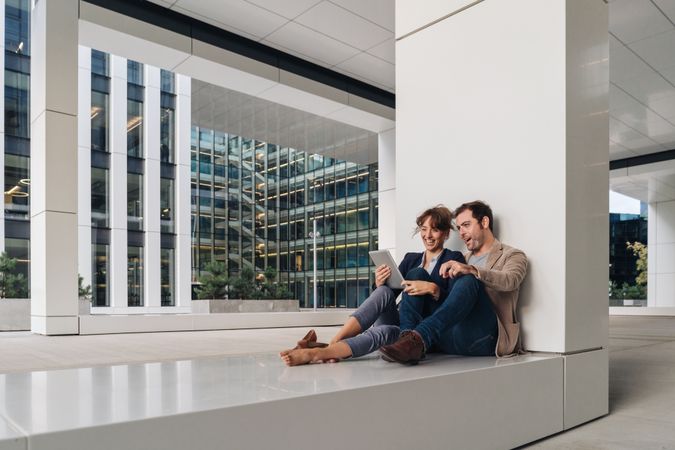 Businesspeople hugging and using tablet on street
