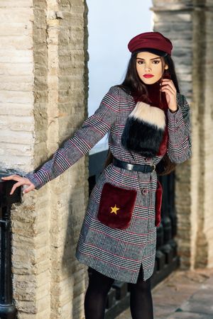 Woman standing in winter clothes next by wall outside