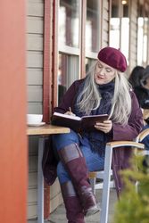 Woman in a beret writing down her ideas into a notebook