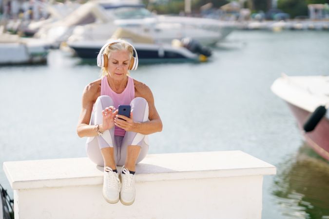 Mature female in sports clothing texting on waterfront