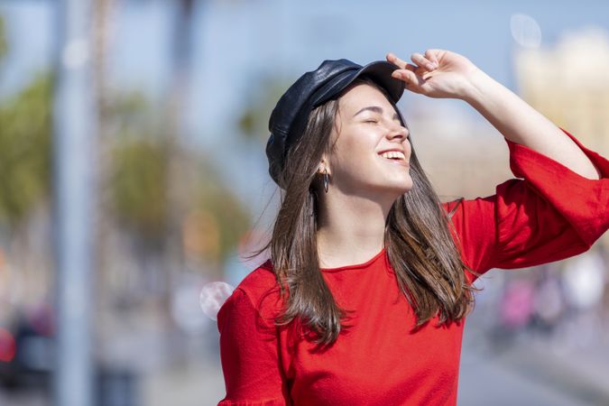 Carefree woman in red shirt smiling in the street on a sunny day