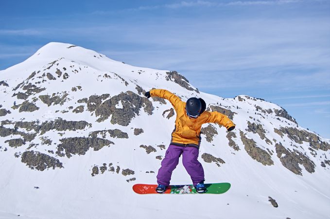 Unrecognizable snowboarder jumping on slope