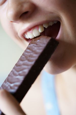 Anonymous teenage girl biting into protein bar